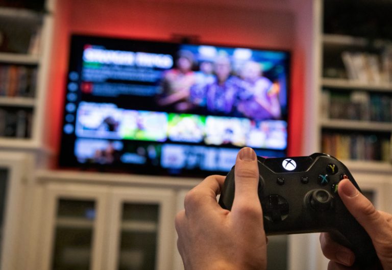 Eine weibliche Hand bedient die Konsole einer Xbox.